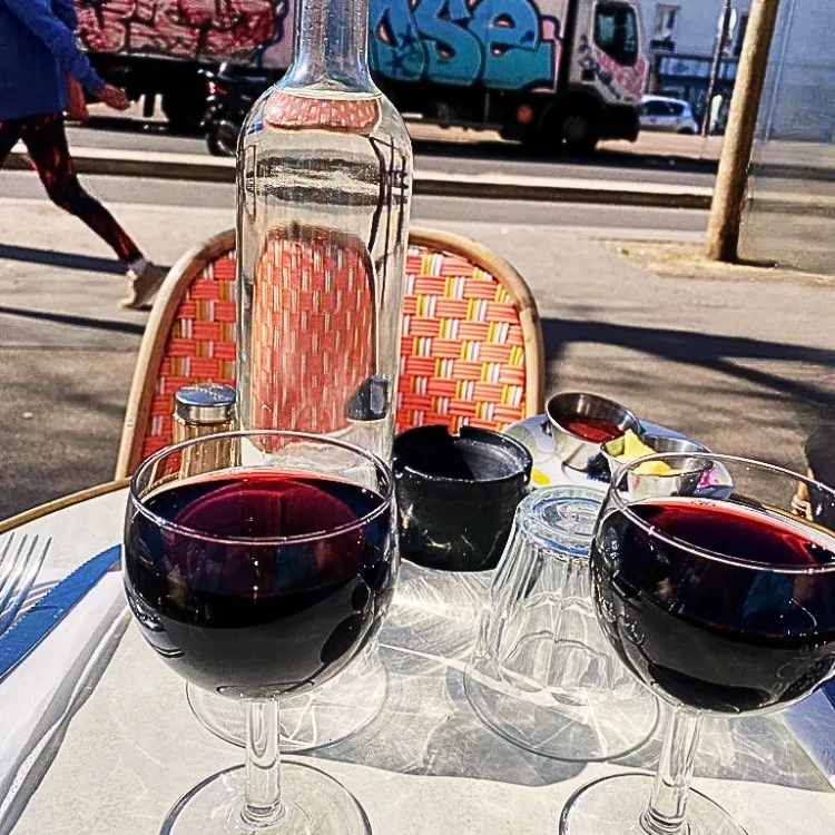 Close-up of two glasses of red wine on a typical Parisian café terrace table, illustrating a relaxed Speed-Frenching conversation session in Paris.